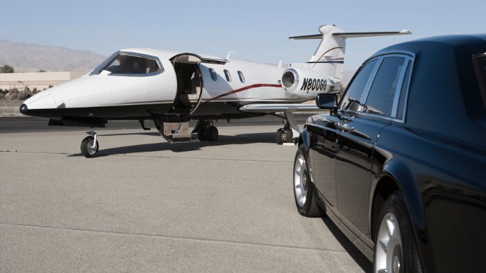 Luxury car parked beside private jet on runway, representing VIP airport transfer service in Santorini for premium travelers.