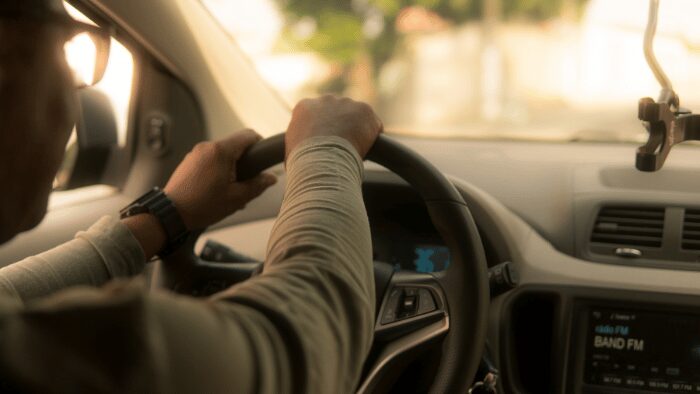 Driver holding steering wheel inside a car during golden hour in Santorini.