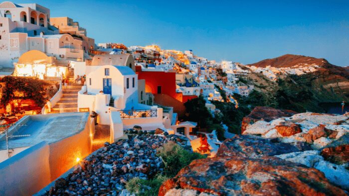 Panoramic view of Oia village in Santorini at sunset with white cave houses and caldera cliffs.