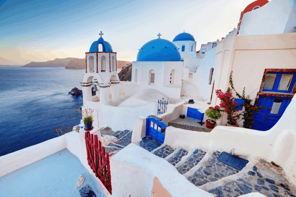 Blue-domed churches and whitewashed buildings on the caldera cliffs of Oia village, Santorini, at sunset
