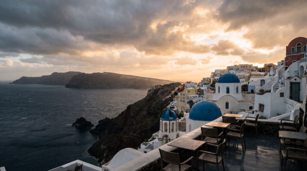 Empty rain-wet cafe terrace in Oia Santorini in November with blue domes under a stormy golden sky